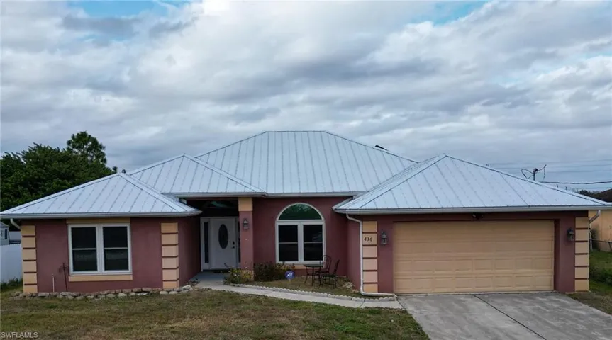 Single story home with 2-car garage, a metal roof, and stucco siding