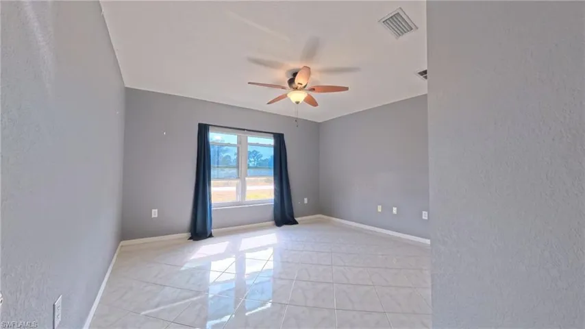 Guest bedroom 1 with tiled floor and ceiling fan