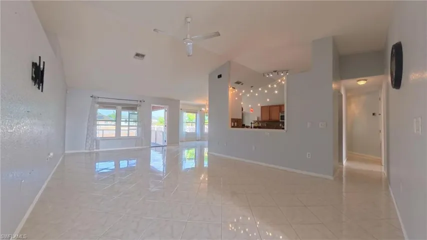 Family room featuring light tile patterned flooring, ceiling fan, and vaulted ceiling