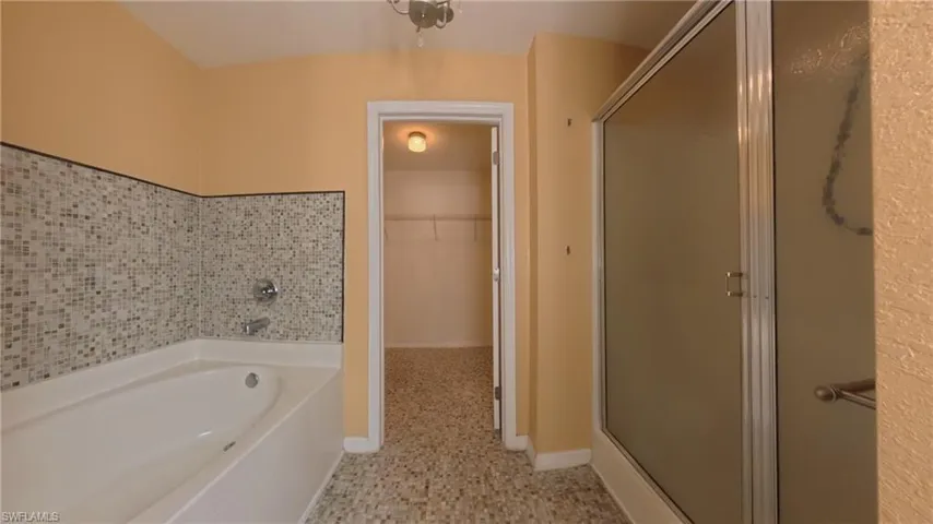 Primary bathroom featuring a spacious closet, a shower stall, and a bath