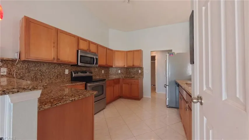 Kitchen with stainless appliances, granite counters & tiled flooring