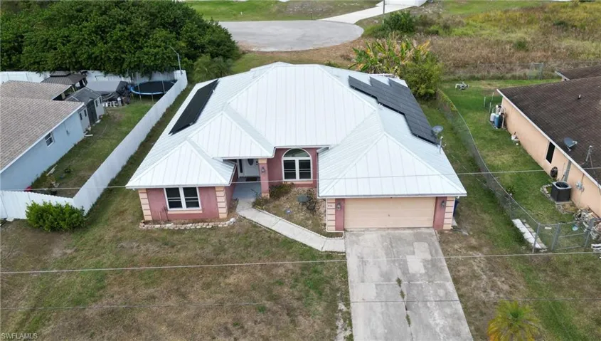 Ariel view of property with metal roof, solar panels and attached garage