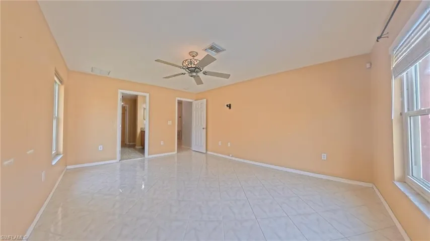 Primary bedroom featuring multiple windows, a ceiling fan, and ensuite bathroom with shower, tub and dual sink