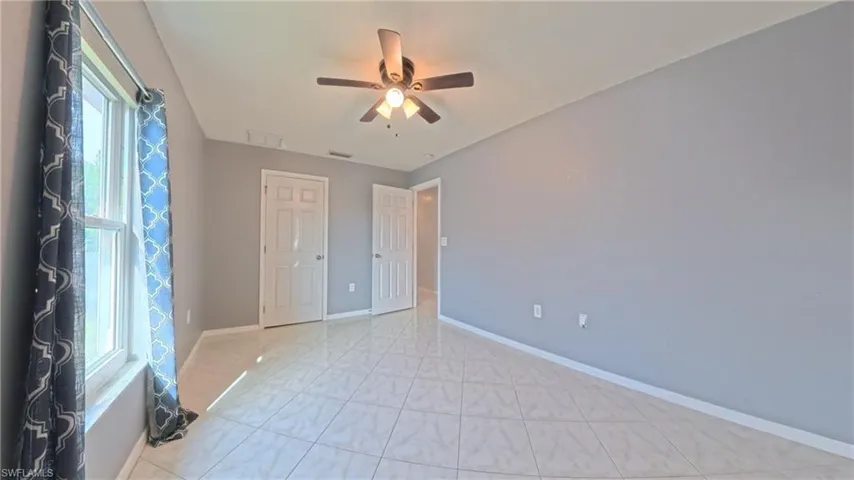 Guest bedroom 2 with ceiling fan and patterned tile floors