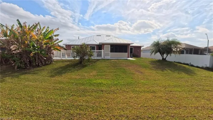 Rear view of house with spacious yard, a fenced pool area, screened lanai, a metal roof, and stucco siding