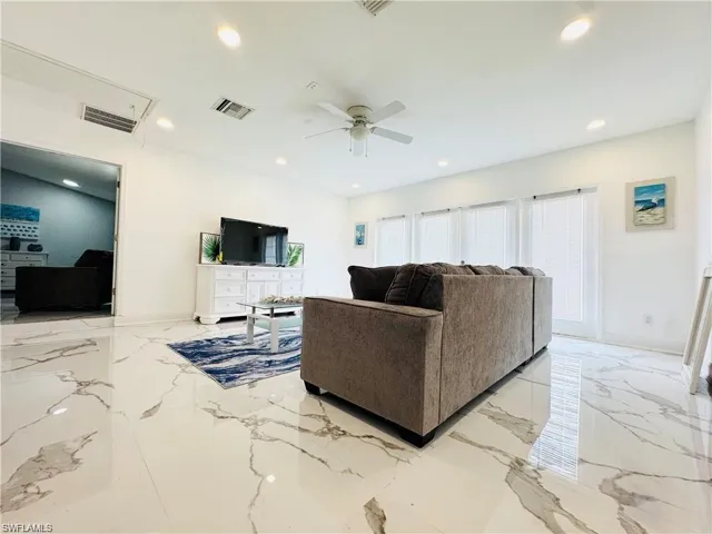 Living room with light marble finish floors, a ceiling fan, and recessed lighting