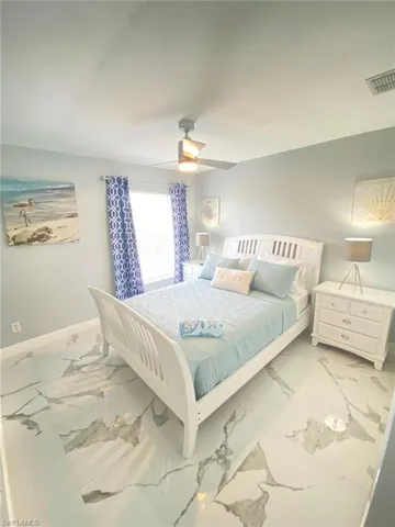 Bedroom featuring ceiling fan and marble finish floors