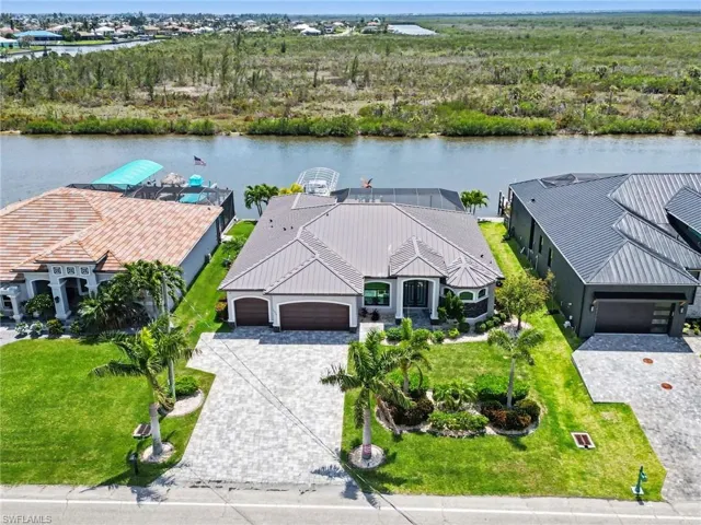 The property features a well-maintained lawn with mature palm trees and a paved driveway