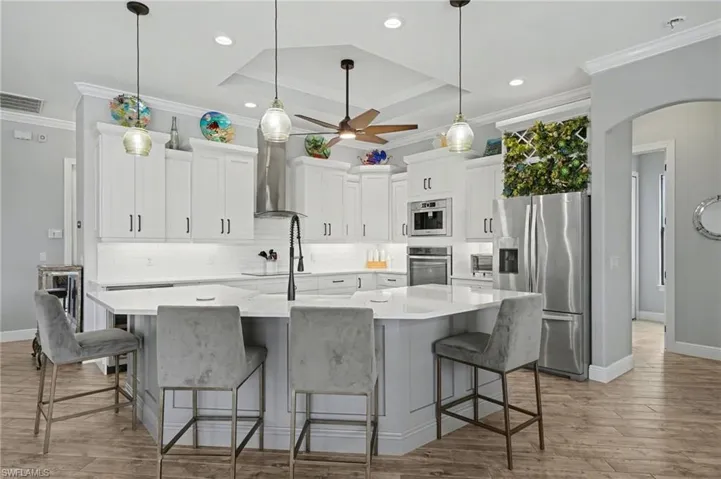 This contemporary kitchen features white cabinetry, a white countertop, and stainless steel appliances