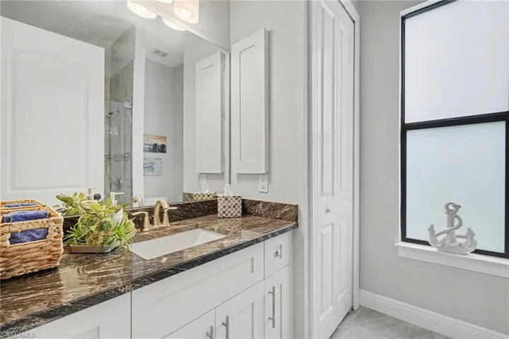 Bathroom featuring a vanity with a dark granite countertop, an undermount sink, and light cabinetry