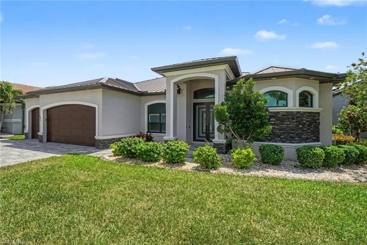 This property features a well-maintained lawn, a paved driveway, and an attached garage