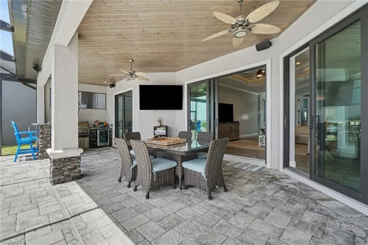 The property features a covered patio with a wood plank ceiling and recessed lighting, along with ceiling fans