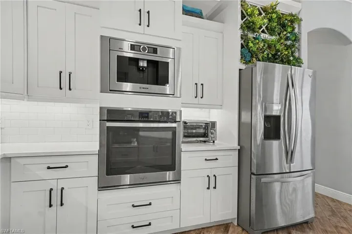 The kitchen features white cabinetry, stainless steel appliances, and a white subway tile backsplash