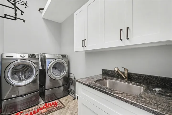 Laundry room with white upper cabinetry, a utility sink, and a granite countertop