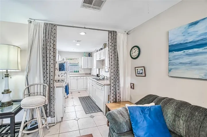 Kitchen featuring white cabinetry, dishwasher, sink, and light tile patterned floors