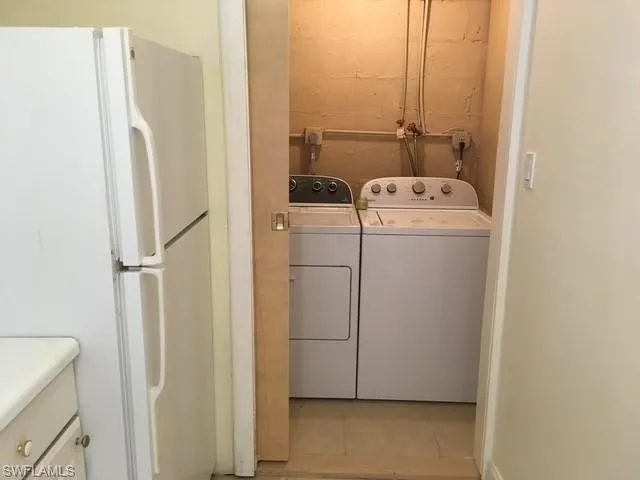 Apt Clothes washing area featuring independent washer and dryer and light tile patterned floors