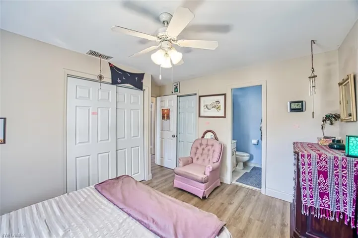 Bedroom featuring multiple closets, ceiling fan, ensuite bath, and light hardwood / wood-style flooring