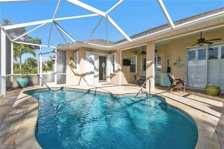 View of swimming pool with ceiling fan, a patio, and a lanai