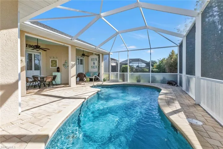 View of swimming pool featuring ceiling fan, glass enclosure, and a patio area