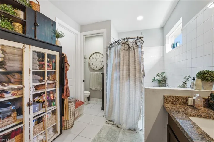 Bathroom with light tile patterned flooring, a shower with shower curtain, and vanity