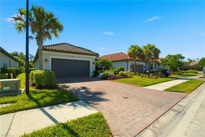 Mediterranean / spanish house featuring stucco siding, decorative driveway, a front lawn, and a tile roof