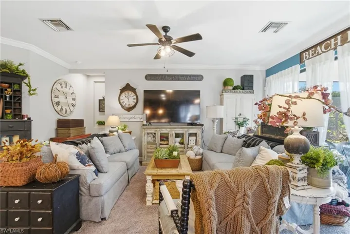Living room featuring crown molding, a ceiling fan, carpet flooring, and a fireplace