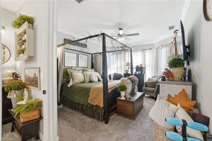 Bedroom featuring carpet flooring, ornamental molding, and a ceiling fan