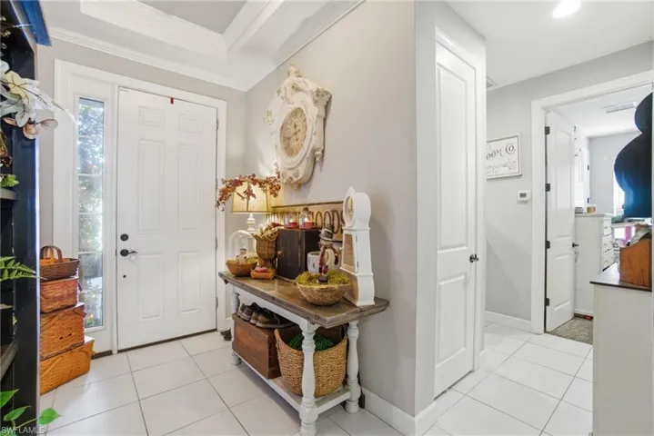Foyer entrance featuring light tile patterned floors and crown molding