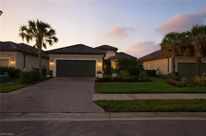Mediterranean / spanish house with stucco siding, decorative driveway, a lawn, an attached garage, and a tiled roof