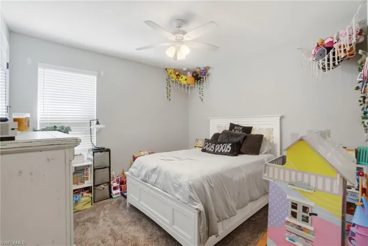 Carpeted bedroom with a ceiling fan