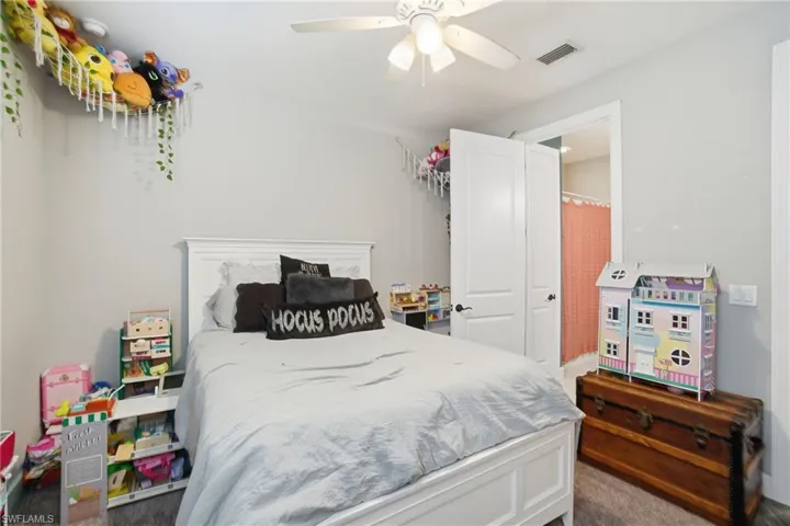 Bedroom with a ceiling fan and dark colored carpet