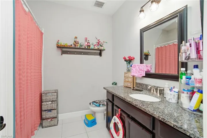 Bathroom featuring light tile patterned floors, curtained shower, and vanity