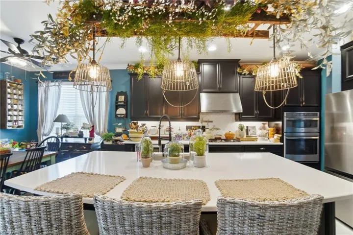 Kitchen featuring a breakfast bar, stainless steel appliances, light stone counters, a kitchen island with sink, and tasteful backsplash