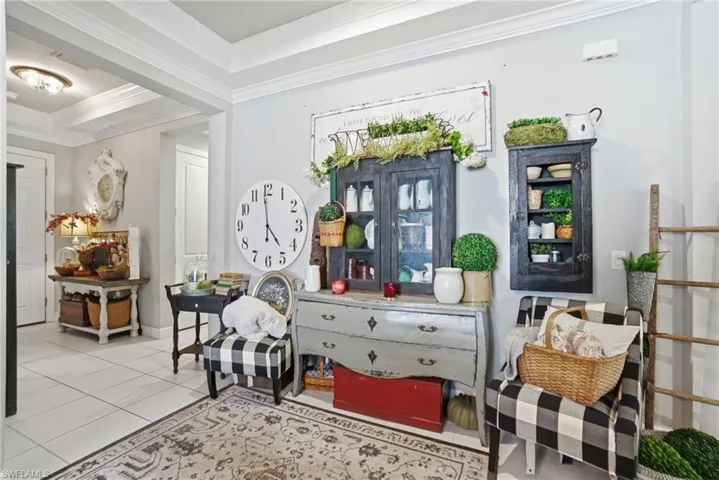Sitting room with tile patterned flooring, crown molding, and a tray ceiling