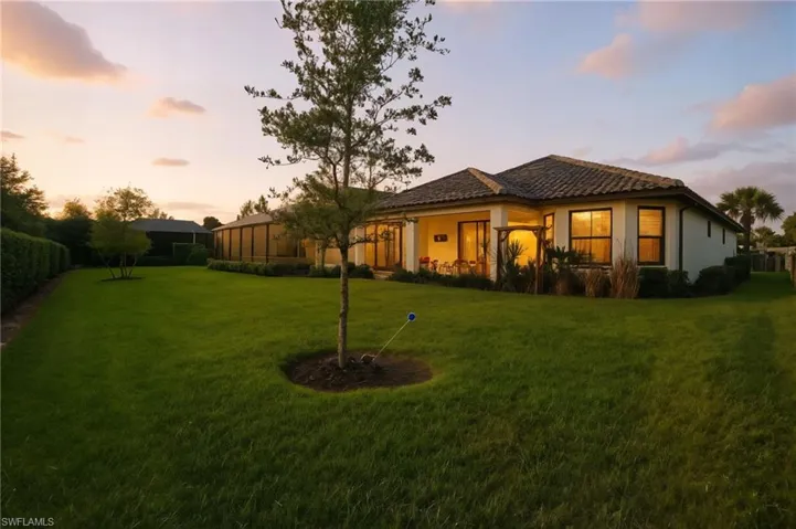 Back of house at dusk with a yard, stucco siding, and a patio area