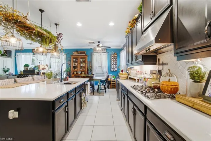 Kitchen featuring under cabinet range hood, tasteful backsplash, open floor plan, light tile patterned flooring, and recessed lighting