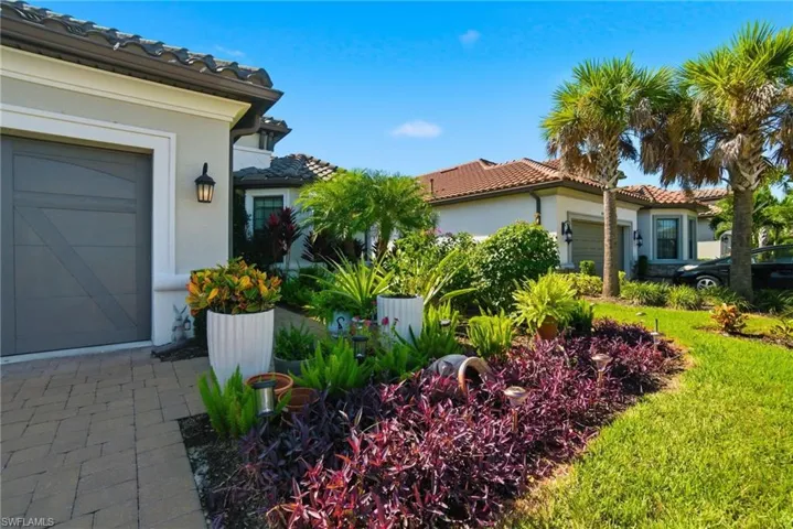 View of side of home featuring a tile roof, stucco siding, a garage, and a yard