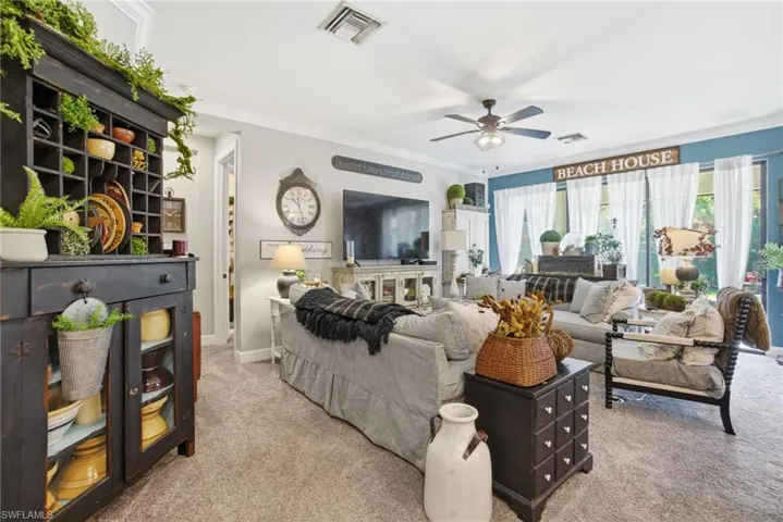 Living area featuring carpet, ornamental molding, and a ceiling fan