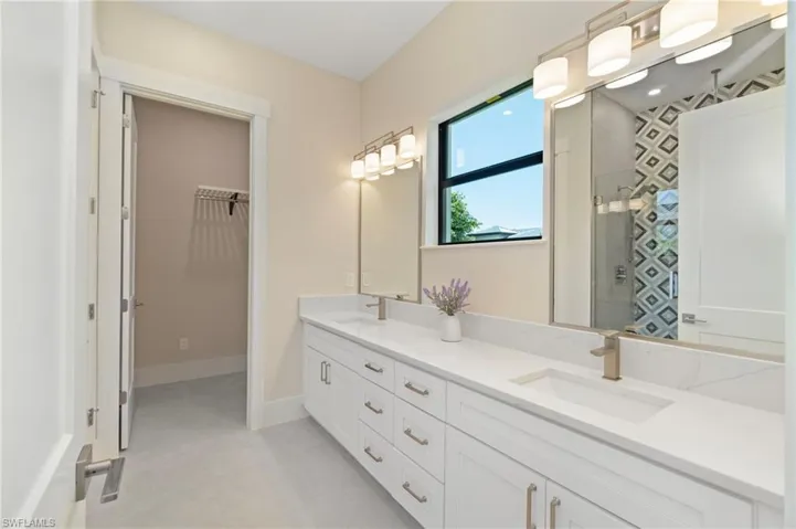 Full bath featuring double vanity, a stall shower, and a spacious closet