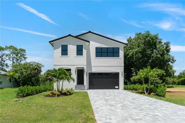 View of front facade with stucco siding, decorative driveway, an attached garage, and a front lawn