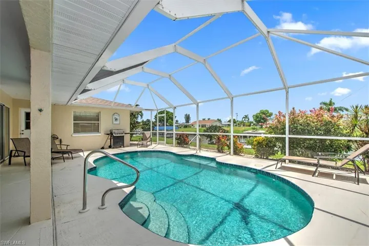 View of swimming pool featuring a patio, glass enclosure, and grilling area