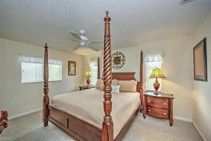 Bedroom featuring light colored carpet, a textured ceiling, and ceiling fan