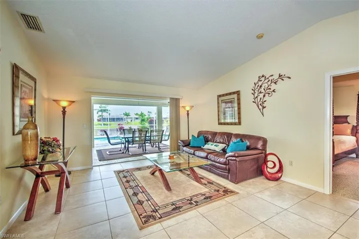 Living room with light tile patterned flooring, a textured ceiling, and vaulted ceiling