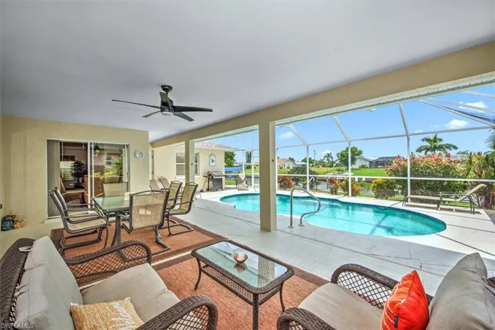 View of swimming pool featuring an outdoor living space, a patio, ceiling fan, and glass enclosure