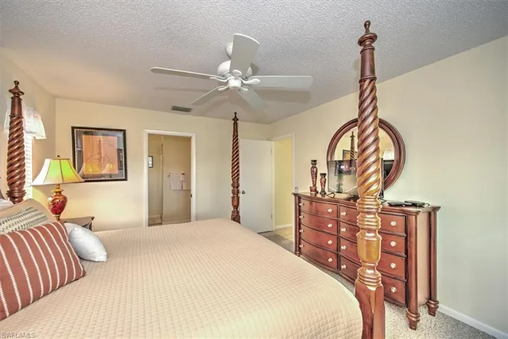 Carpeted bedroom with a textured ceiling and ceiling fan