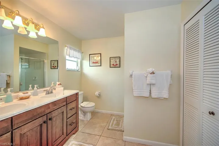 Bathroom featuring tile patterned flooring, toilet, and dual bowl vanity