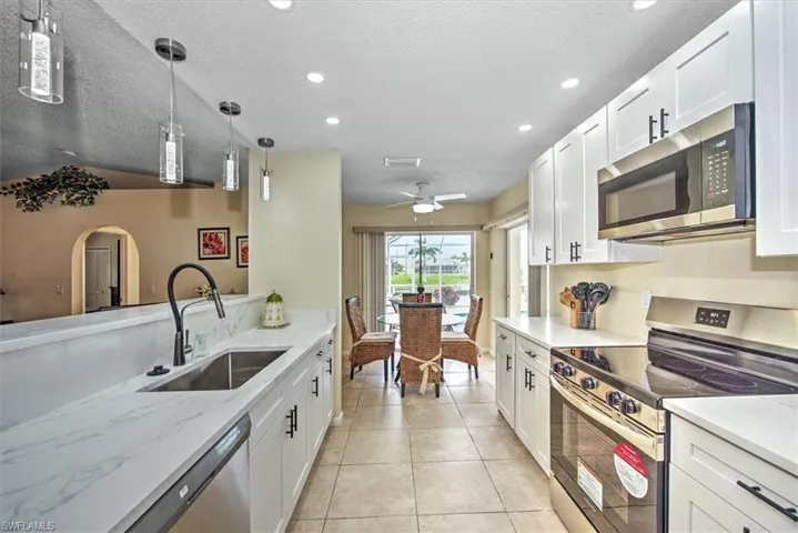Kitchen featuring appliances with stainless steel finishes, white cabinetry, light stone countertops, and sink
