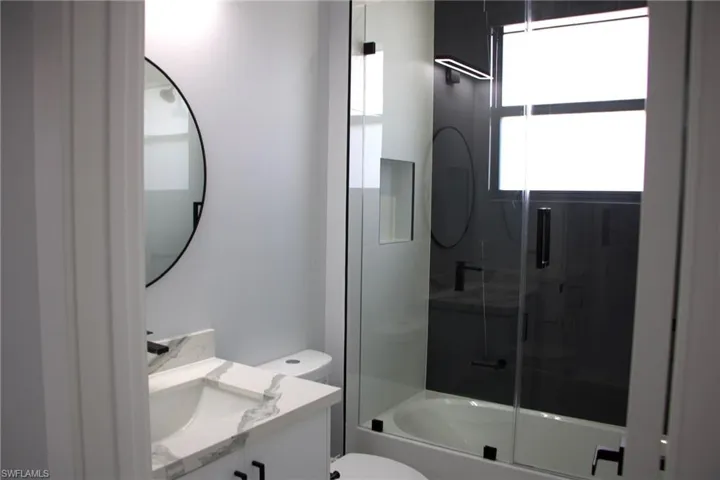 Bathroom featuring vanity and combined bath / shower with glass door