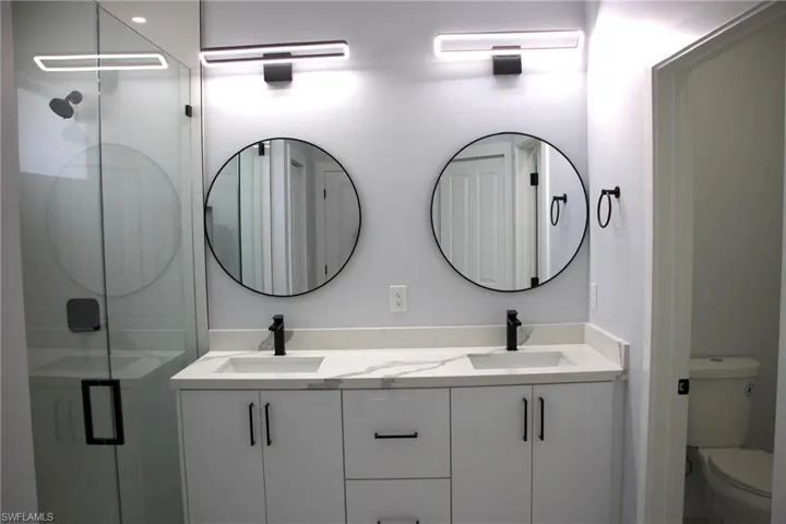 Full bathroom with double vanity and a shower stall