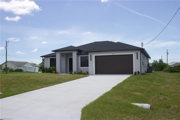 Prairie-style house featuring a front lawn, stucco siding, driveway, and a garage